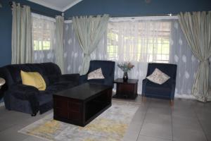 a living room with two blue couches and a coffee table at Sable Holiday Home in Hazyview