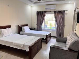 Habitación con 2 camas, sofá y ventana en Royal Blue Inn House, en Islamabad