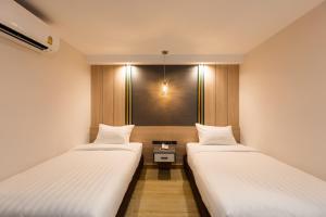 two beds in a small room with a window at City Park Hotel Bangkok Pratunam by PCL in Bangkok