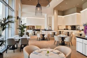a restaurant with tables and chairs and a kitchen at Address Dubai Marina - 1B Apt, Full Marina View with 5 Star Hotel Facilities by Gardenia Suites in Dubai