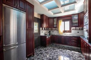 a kitchen with wooden cabinets and a stainless steel refrigerator at Oceanviewvilla in Karpathos