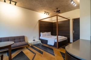 una camera da letto con un letto e un divano in una stanza di Walk to Calangute beach from this beautiful studio a Calangute