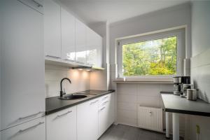 cocina blanca con fregadero y ventana en Blue Sky Apart Center Baden-Baden en Baden-Baden