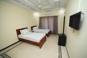 1 dormitorio con 2 camas y TV de pantalla plana en Royal Blue Inn House, en Islamabad