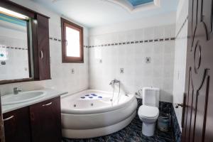 a bathroom with a tub and a toilet and a sink at Oceanviewvilla in Karpathos