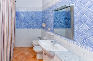 a blue tiled bathroom with a sink and a toilet at Appartamento incantevole con vista mare in Buoncammino