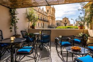 a patio with tables and chairs and a view of a building at Q92 Noto Hotel in Noto