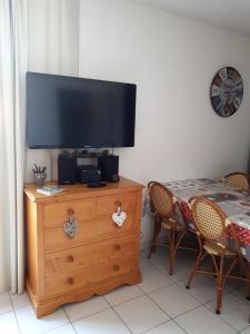 a television on top of a wooden dresser with a table and chairs at Charming Apt With Balcony In La Plagne Montalbert in La Plagne