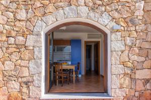 an archway in a stone wall with a dining room at Appartamento incantevole con vista mare in Buoncammino