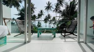 a balcony with a table and two chairs and palm trees at Villa LA Kurumba in Ambalangoda