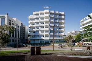 a tall white apartment building in a city at Residence Hotel Piccadilly in Rimini