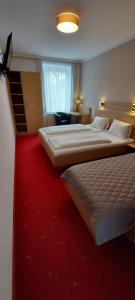 a hotel room with two beds and a red carpet at Gasthof Grünling in Wallsee