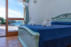 a bedroom with a bed with blue sheets and a window at Appartamento incantevole con vista mare in Buoncammino