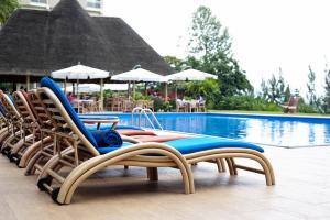 a person sitting on a bench in front of a pool at Hotel des Mille Collines in Kigali