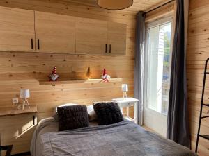 1 dormitorio con paredes de madera, 1 cama y ventana en Charmant T2 en plein centre de Formiguères, en Formiguères