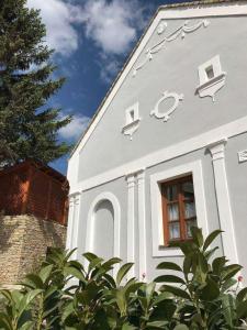 una casa blanca con una ventana y un árbol en Arácsi Vendégház, en Balatonfüred