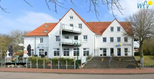 un bâtiment blanc avec un toit rouge dans l'établissement Haus am Dorfbrunnen Ferienwohnung Meer, à Wangerooge