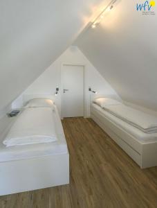 ein weißes Zimmer mit zwei Betten in einem Dachgeschoss in der Unterkunft Haus am Dorfbrunnen Ferienwohnung Düne in Wangerooge