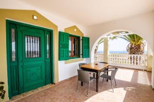 a dining room with green doors and a table and chairs at Oceanviewvilla in Karpathos
