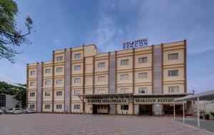a large tan building with a sign on top of it at Guruprerna Beacon Resort, Dwarka in Dwarka
