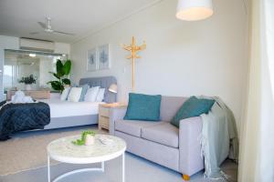 a living room with a bed and a couch and a table at Pacific Blue Whitsunday - Studio in Airlie Beach