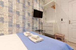 1 dormitorio con toallas en una cama y TV en Beach Hut * Green oasis with private patio 10 min to Palais & beaches * Pet Friendly, en Cannes
