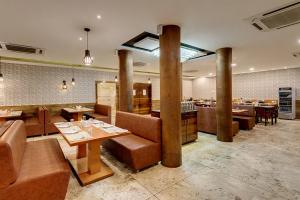 un restaurante con mesas y sillas en una habitación en Guruprerna Beacon Resort, Dwarka en Dwarka