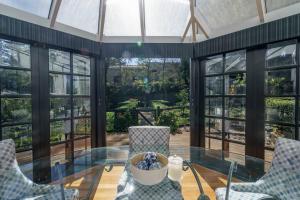 a conservatory with a glass table and chairs and windows at Bryn-y-Mor Cottage Romantic Fireplace Couples in Leura