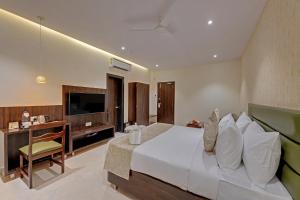 a hotel room with a bed and a television at Guruprerna Beacon Resort, Dwarka in Dwarka