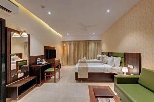 Habitación de hotel con cama y sofá verde en Guruprerna Beacon Resort, Dwarka en Dwarka