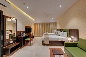 德瓦尔卡Guruprerna Beacon Resort, Dwarka的酒店客房,设有一张床铺和一张绿色沙发