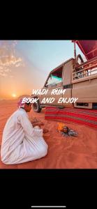 瓦迪拉姆的住宿－Desert Moon Camp，坐在一辆面包车旁的沙漠中的女人