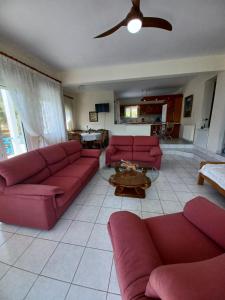 a living room with red couches and a ceiling fan at Gaby's Villa in Koinyra