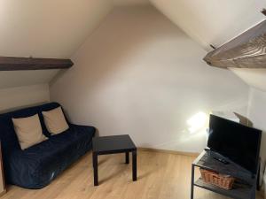 ein Wohnzimmer mit einem blauen Sofa und einem TV in der Unterkunft La Ferme Des Eglantines in Nivelles