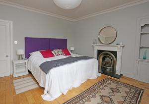a bedroom with a bed with a purple headboard and a fireplace at Rooftops in North Berwick