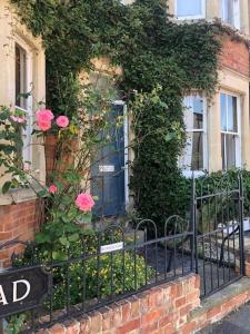 a fence in front of a house with pink roses at Charming Victorian Townhouse in Oxford Center in Oxford