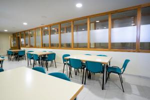 a classroom with tables and chairs and windows at Albergue Inturjoven Sierra Nevada in Sierra Nevada