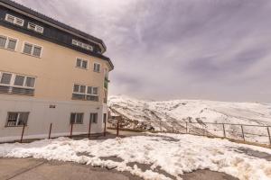a building with snow in front of a mountain at Albergue Inturjoven Sierra Nevada in Sierra Nevada