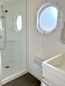 a white bathroom with a shower and a round window at Roccapina in Lumio