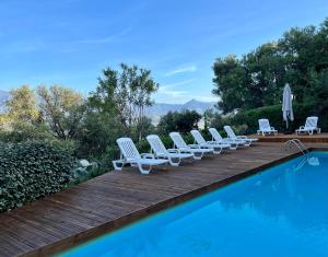 a group of chairs sitting on a wooden deck next to a swimming pool at Roccapina in Lumio