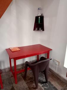 einen roten Schreibtisch mit einem schwarzen Stuhl neben einer Wand in der Unterkunft THE SILVER OAK PLACE in Pithorāgarh