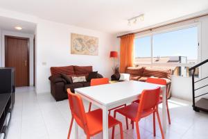 ein Wohnzimmer mit einem weißen Tisch und orangefarbenen Stühlen in der Unterkunft Home2Book Duplex El Medano Pool & Terrace in El Médano