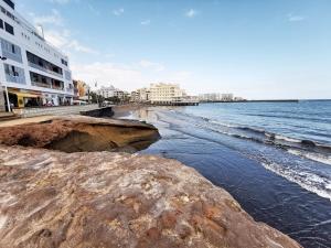 Blick auf einen Strand mit Gebäuden und das Meer in der Unterkunft Home2Book Duplex El Medano Pool & Terrace in El Médano