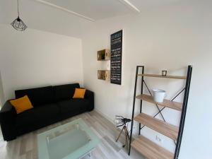 a living room with a black couch and a shelf at Chambre indépendante chez l'habitant in Nîmes