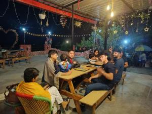 a group of people sitting at a table in a restaurant at Kumaon Roadies Adventure Camp & Resort in Mukteshwar