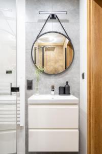 uma casa de banho com um espelho e um lavatório branco em Apartamenty Harenda Zakopane em Zakopane