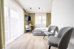 a room with a bed and two chairs and a table at Apartamenty Harenda Zakopane in Zakopane