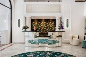 a woman standing in a lobby with a glass table at The 1932 Hotel & Spa Cap d'Antibes - MGallery Collection in Juan-les-Pins