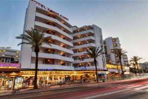 a building with palm trees in front of a street at Hotel Xaine Park in Lloret de Mar