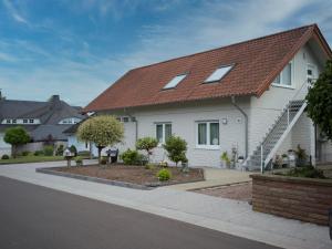 une maison blanche avec un toit rouge dans l'établissement Ferienwohnung Sonnenblick in Losheim am See, à Losheim